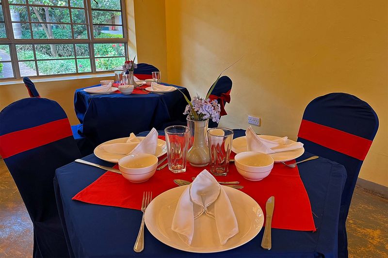 Table set for a meal with navy chair covers and red runner