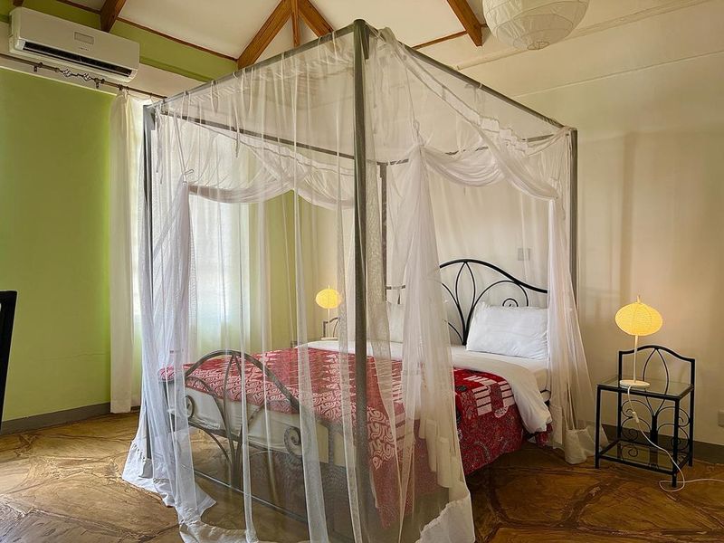 Canopy bed with red bedding and an air conditioner on the wall