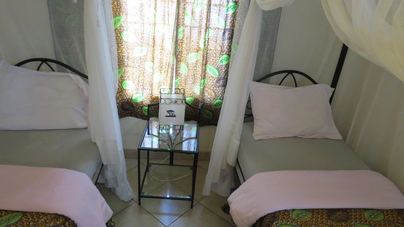 Two single beds with mosquito nets and a glass side table